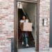 Young woman moving boxes out of an apartment building. Ideal for relocation and moving day themes.
