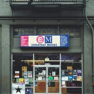 Facade of a music store displaying various posters and albums in an urban setting.