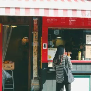 A quaint coffee shop with a striped awning in Seoul's Bukchon Hanok Village captures local charm.