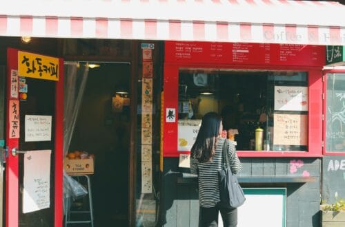 A quaint coffee shop with a striped awning in Seoul's Bukchon Hanok Village captures local charm.